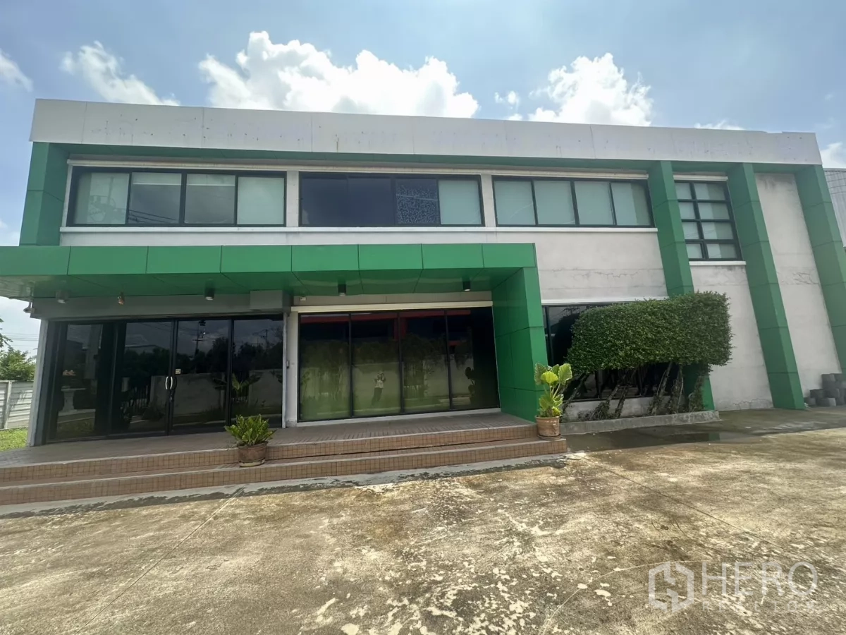 Warehouse for sale in Bang Len, Nakhon Pathom - Two-storey warehouse office facade with green panels, wide glass entrance and steps.