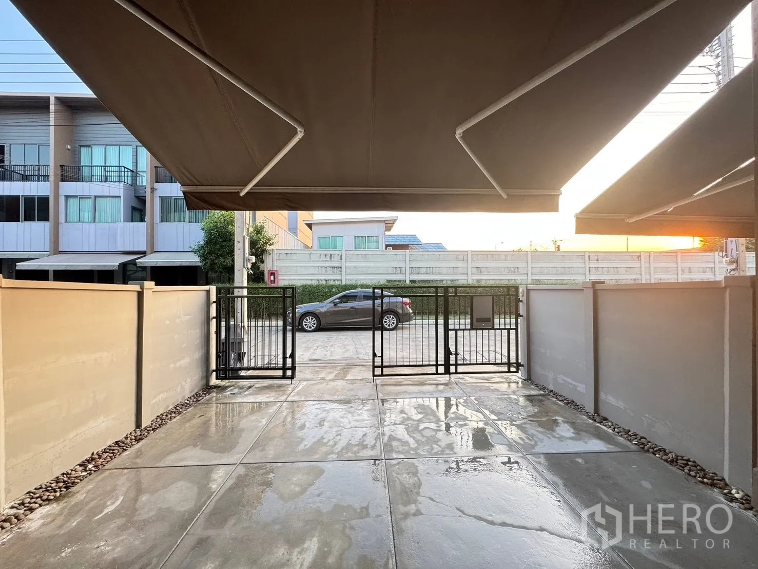Townhouse for rent in Saphan Sung, Bangkok - Covered front carport with metal gate and concrete driveway.