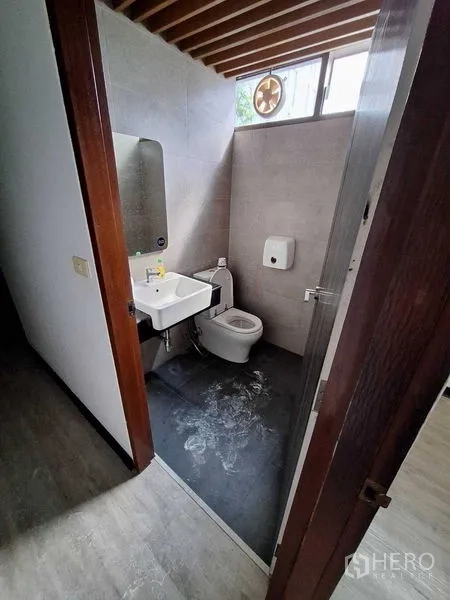 Office Space for rent in Watthana, Bangkok - Modern bathroom with toilet, basin, ventilation fan and slatted ceiling detail.