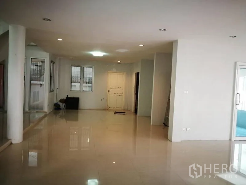 独立式住宅 出租在Phra Khanong, Bangkok - 宽敞的开放式客厅，亮面地砖、白墙与嵌灯。