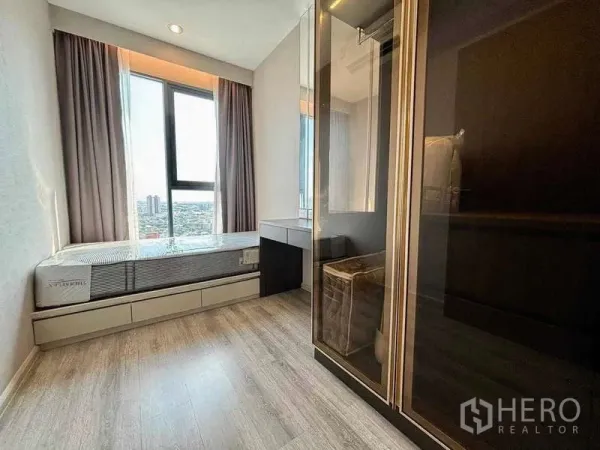 公寓 出租或出售在Bang Na, Bangkok - 次卧配单人床、玻璃门衣柜与大窗户，享城市景观。