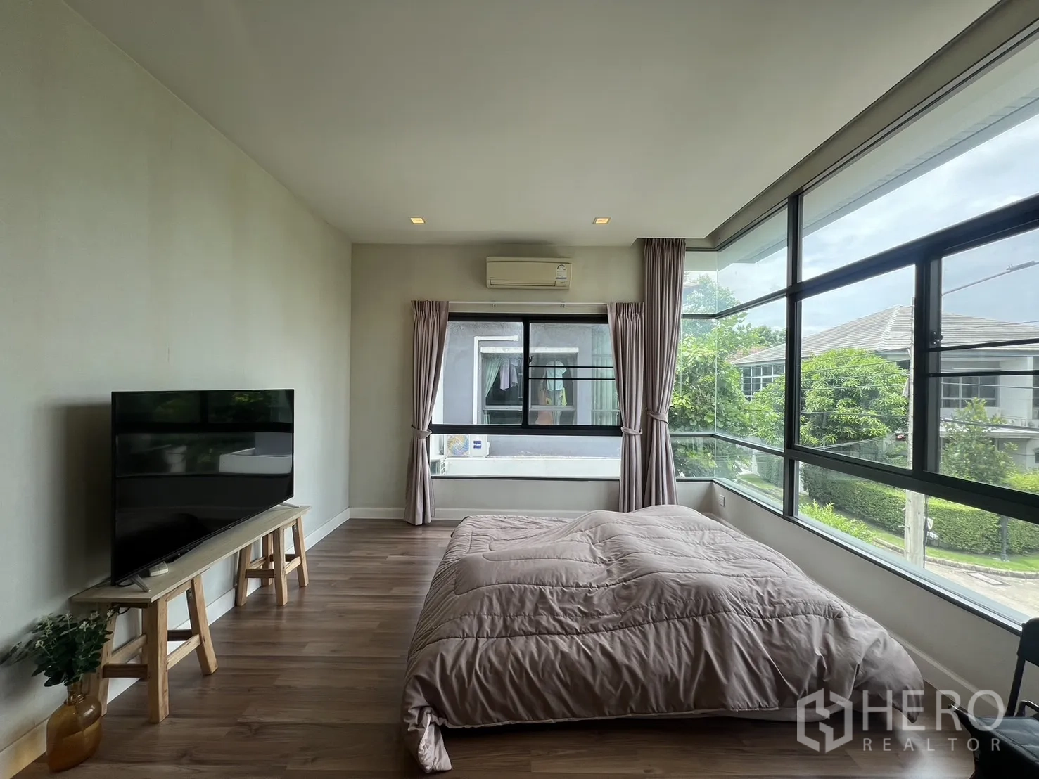 Detached House for rent in Bang Kapi, Bangkok - Bedroom with TV bench facing bed and wrap-around windows.