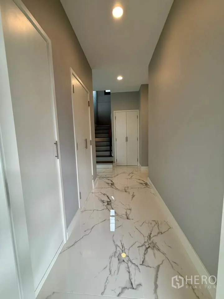 Detached House for rent in Don Mueang, Bangkok - Ground-floor corridor with glossy marble-look tiles and storage closets.