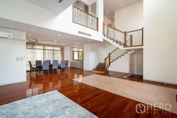 บ้าน ให้เช่าในWatthana, Bangkok - ห้องนั่งเล่นเพดานสูงสองชั้น พื้นไม้และบันไดเด่นในบ้านเดี่ยวเขตวัฒนา กรุงเทพฯ.