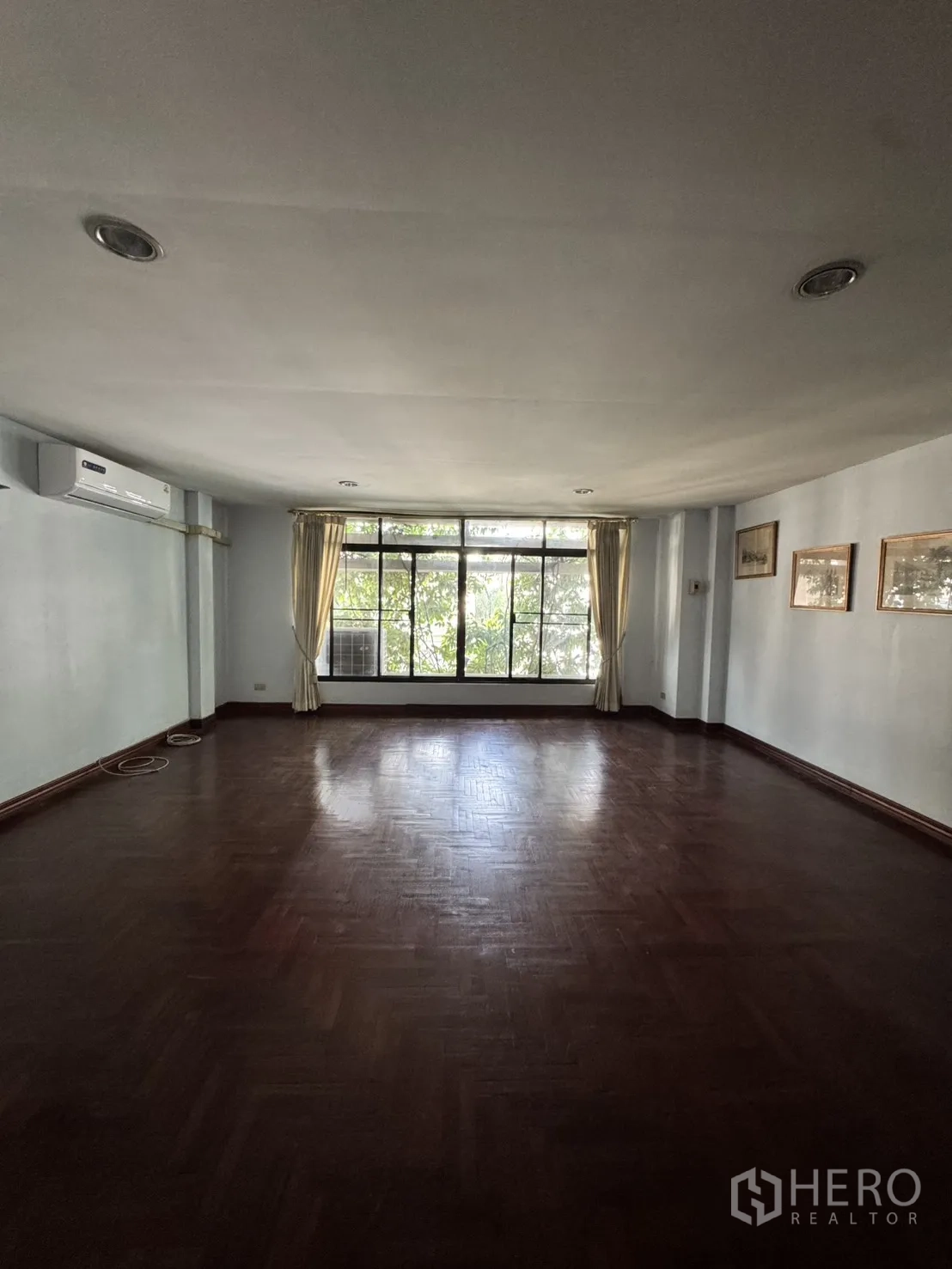 โฮมออฟฟิศ for rent in Watthana, Bangkok - ห้องกว้างปูพื้นปาเก้สีเข้ม หน้าต่างบานใหญ่ ม่าน และแอร์ติดผนัง