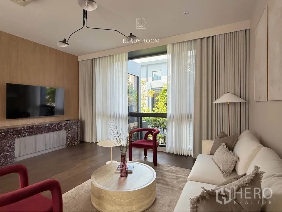 Detached House for rent in Bang Kapi, Bangkok - Modern living room with TV wall, marble console, floor‑to‑ceiling curtains and garden view.