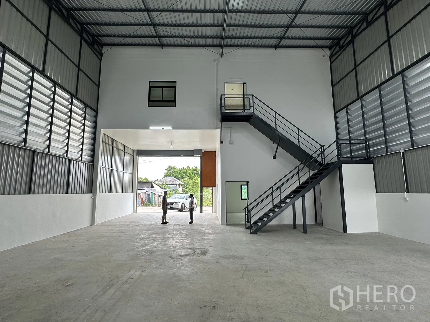 Warehouse for rent or sale - Central hall toward a large doorway and stair‑access office block.