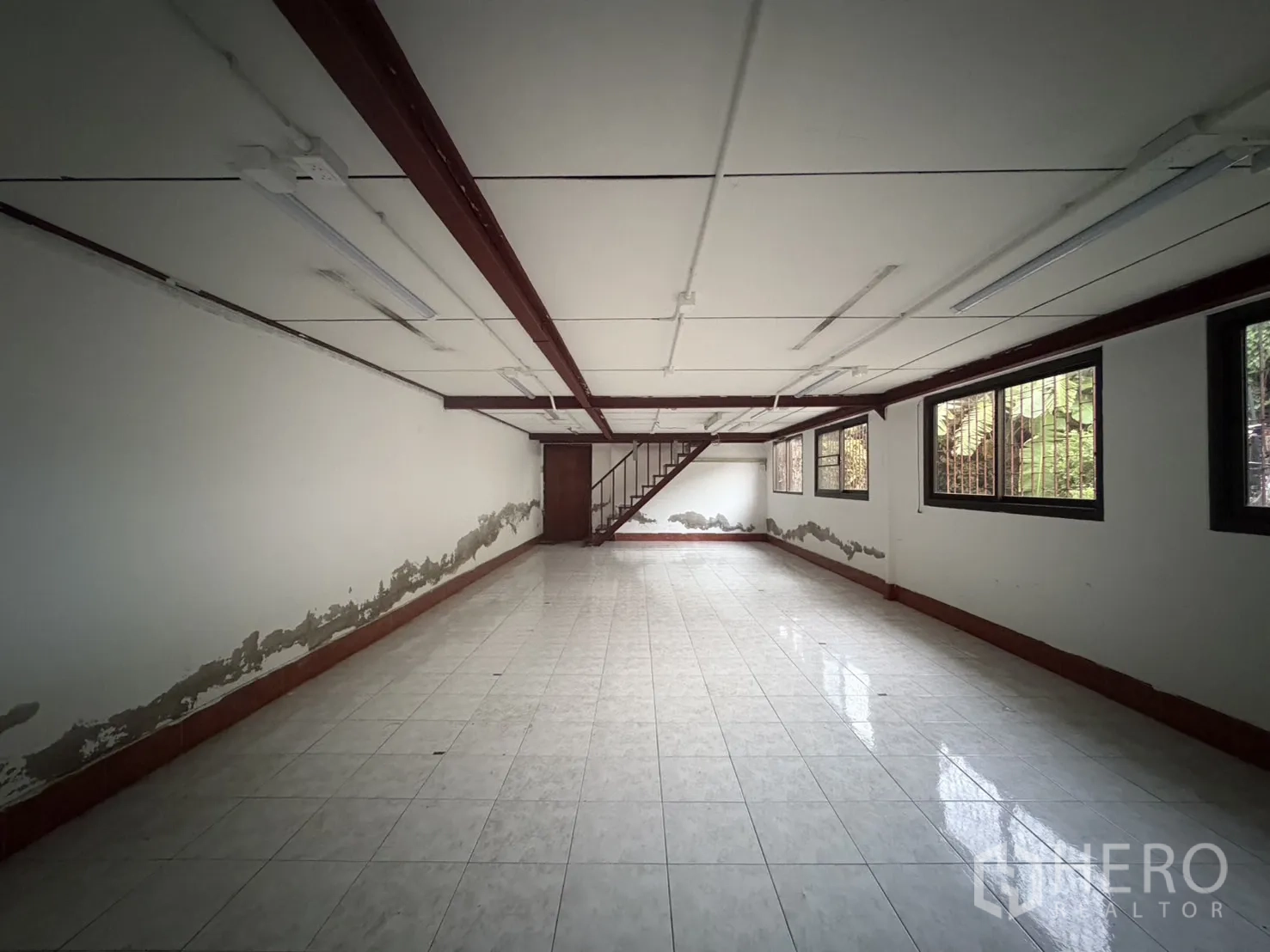 货栈 出租在Mueang Samut Prakan, Samut Prakan - 开放式办公室楼层，瓷砖地面，带栏杆窗与通往二层的楼梯。