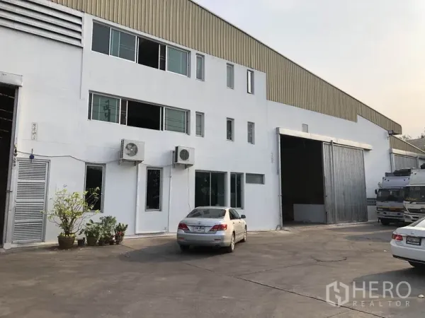 工厂 出租在Bang Bua Thong, Nonthaburi - 邦布通两层厂房外观，宽大型滑动门与现场停车区。