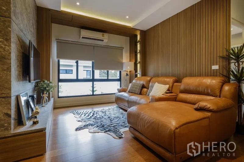Detached House for rent in Phasi Charoen, Bangkok - Media room with leather sectional sofa, TV wall and warm wood paneling.