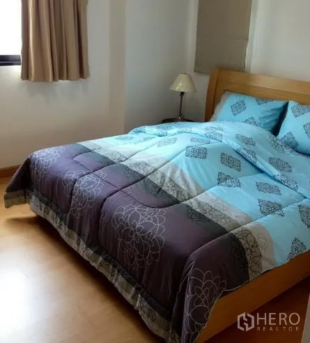 Condominium for rent in Watthana, Bangkok - Master bedroom with wood flooring, a queen bed, and a window bringing in natural light.