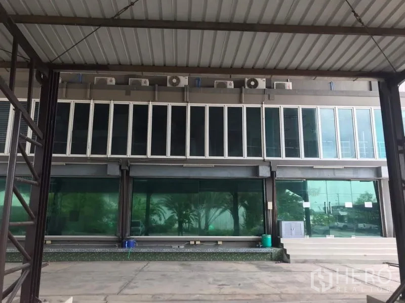Home Office for sale in Khlong Luang, Pathum Thani - Glass-fronted office block with multiple air-conditioning units beneath a covered canopy.