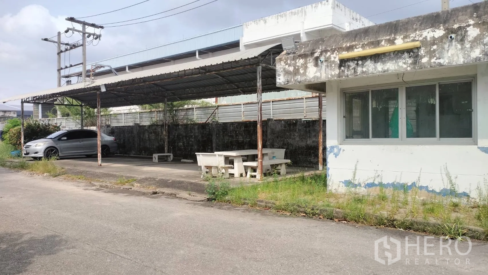 Factory for rent in Lat Krabang, Bangkok - Guardhouse and covered parking area with benches beside the boundary wall.