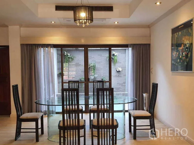 ทาวน์เฮาส์ ให้เช่าในKhlong Toei, Bangkok - ห้องอาหารโต๊ะกระจกทรงวงรี เก้าอี้หกตัวและประตูกระจกสไลด์สู่ลาน