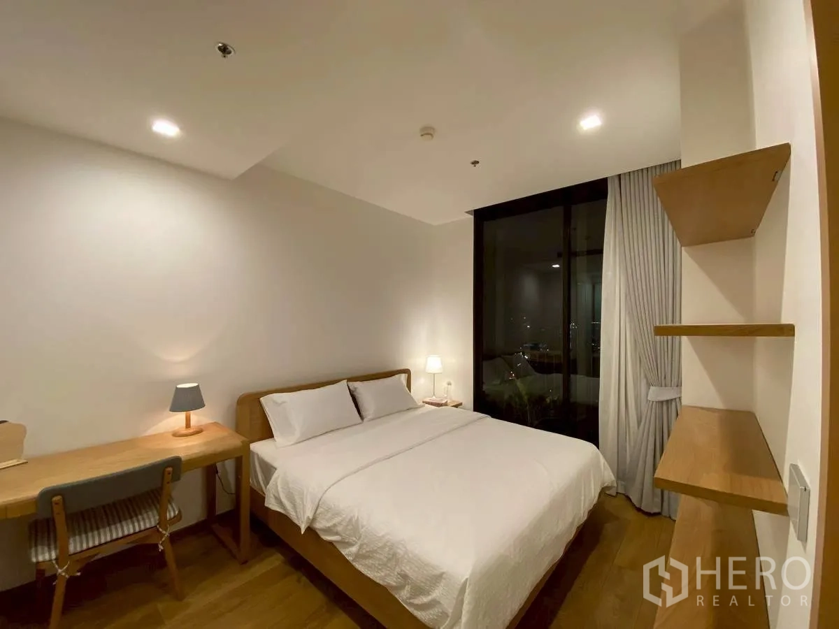 Condominium for rent in Watthana, Bangkok - Cozy second bedroom with desk, lamps, and large window for night views.