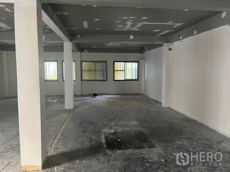 零售空间 出租在Pathum Wan, Bangkok - 开放式零售楼层，多扇窗户、白墙与灰色梁。