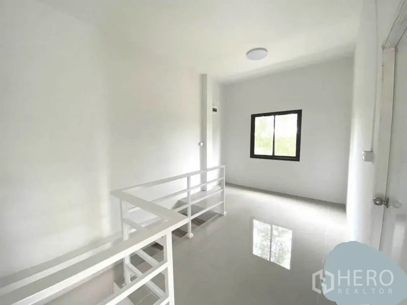 Warehouse for rent in Lat Lum Kaeo, Pathum Thani - Upstairs landing with white railing and a window bringing in natural light.