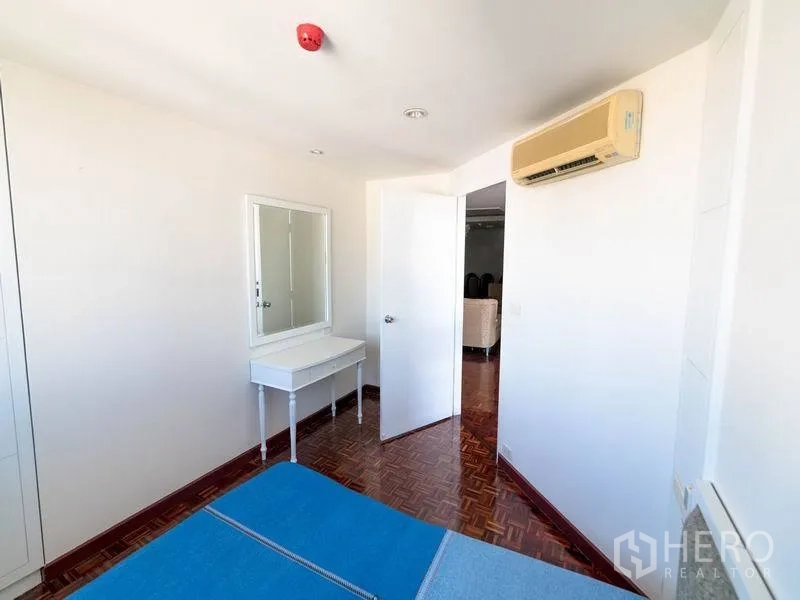 Condominium for rent in Watthana, Bangkok - Cozy bedroom with vanity, built-in wardrobe, and wall-mounted air conditioner.
