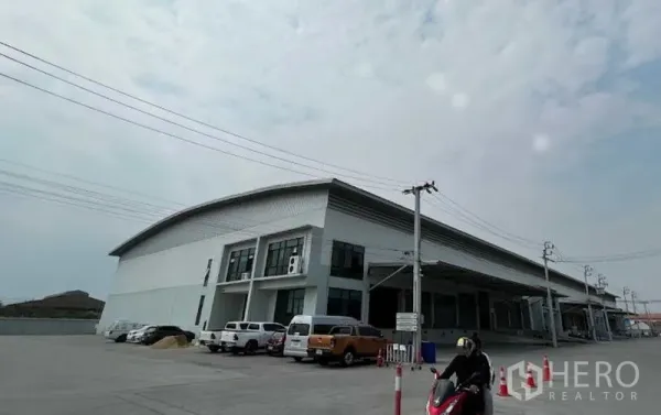 Warehouse for rent in Bang Bo, Samut Prakan - Modern high-clearance warehouse exterior with multiple covered loading bays, raised docking platform, and wide parking area in an industrial zone of Bang Bo, Samut Prakan.