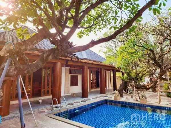 Detached House for sale in Bueng Kum, Bangkok - Courtyard with blue-tiled private pool, mature frangipani tree and wooden pillars.