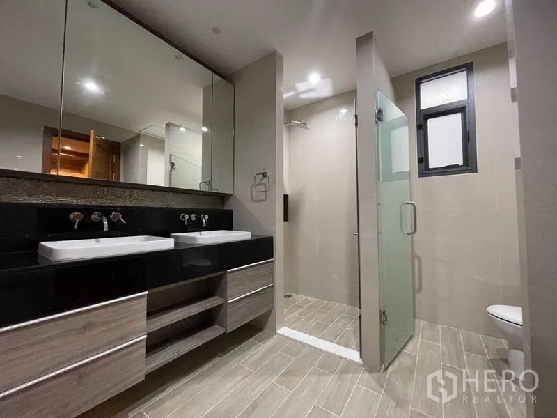 Detached House for rent in Bang Na, Bangkok - Bathroom with twin sinks, wide mirror and glass-enclosed shower.