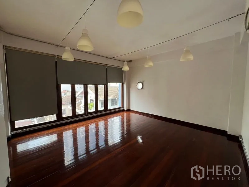 Office Space for rent in Watthana, Bangkok - Corner office room with roller blinds, round porthole window, pendant lights, and glossy wood floor.