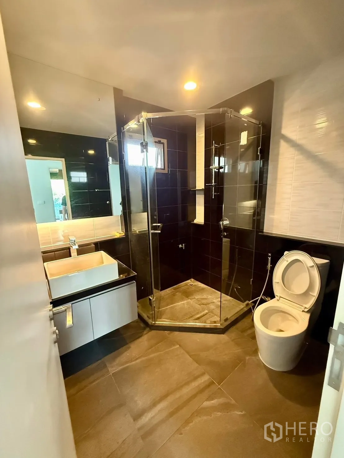 Detached House for rent in Bang Kapi, Bangkok - Bathroom with glass-enclosed shower, vanity and dark tile flooring.