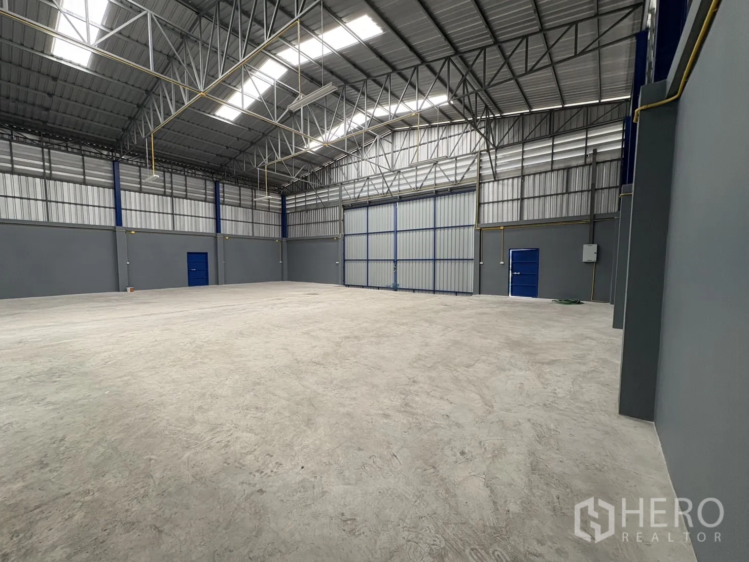 คลังสินค้า ให้เช่าในBang Phli, Samut Prakan - โกดังเพดานสูงมีสกายไลต์ คานเหล็ก ประตูทางเข้าสีน้ำเงิน และประตูบานเลื่อนขนาดใหญ่