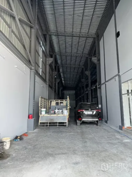 Warehouse for rent in Bang Khun Thian, Bangkok - Deep warehouse bay under a metal roof with space for vehicles and pallets.