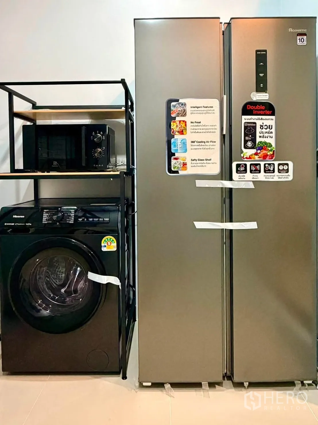 Townhouse for rent in Bang Phli, Samut Prakan - Appliance corner featuring a front-load washer, microwave on a rack, and a large side-by-side refrigerator.
