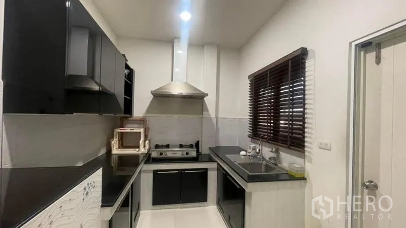 บ้าน ให้เช่าหรือขายในPrawet, Bangkok - ครัวปิดแบบแกลเลย์ ตู้สีดำ เตาแก๊ส เครื่องดูดควัน และซิงก์คู่