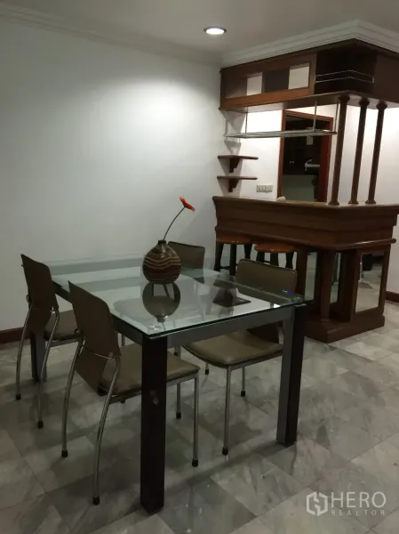 Condominium for rent or sale in Watthana, Bangkok - Dining area with a glass table, four chairs and a built-in wooden bar shelf.