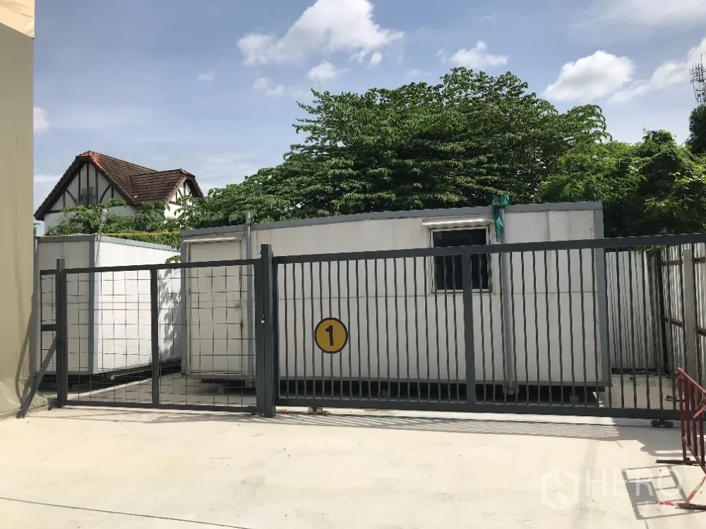 Warehouse for rent in Huai Khwang, Bangkok - Secure metal gate with site cabins inside the compound at the warehouse entrance.