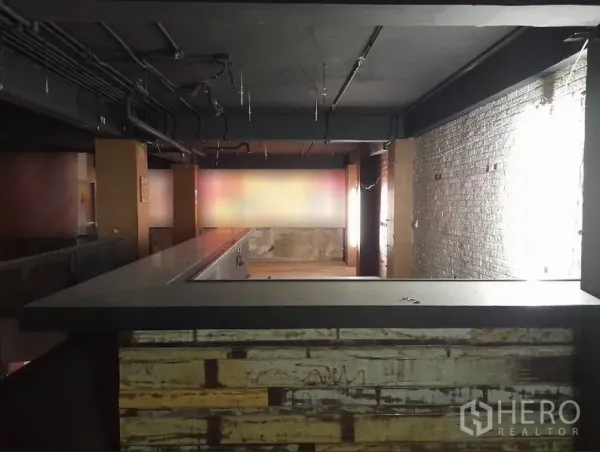 Shophouse for rent - Long bar counter on the mezzanine with exposed brick wall and track lighting.