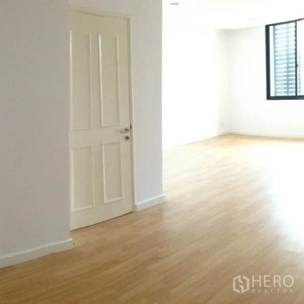 Townhouse for rent in Yan Nawa, Bangkok - Sunlit room with wood floors, white door, and a corner window.