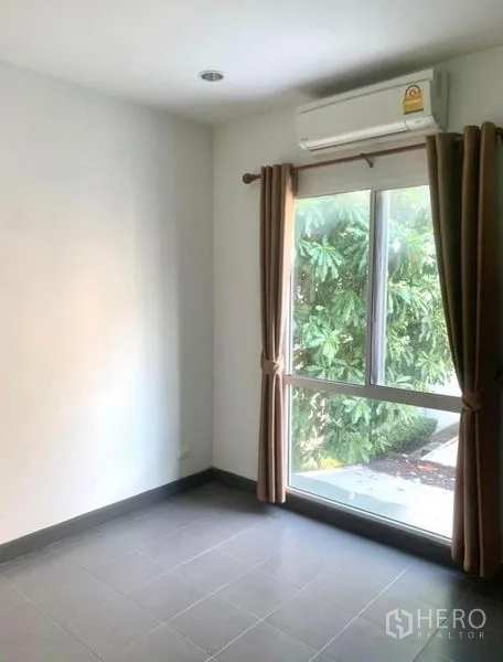 ทาวน์เฮาส์ ให้เช่าในSuan Luang, Bangkok - ห้องชั้นล่างพร้อมหน้าต่างบานใหญ่ ผ้าม่านสีน้ำตาล เครื่องปรับอากาศ มองเห็นต้นไม้
