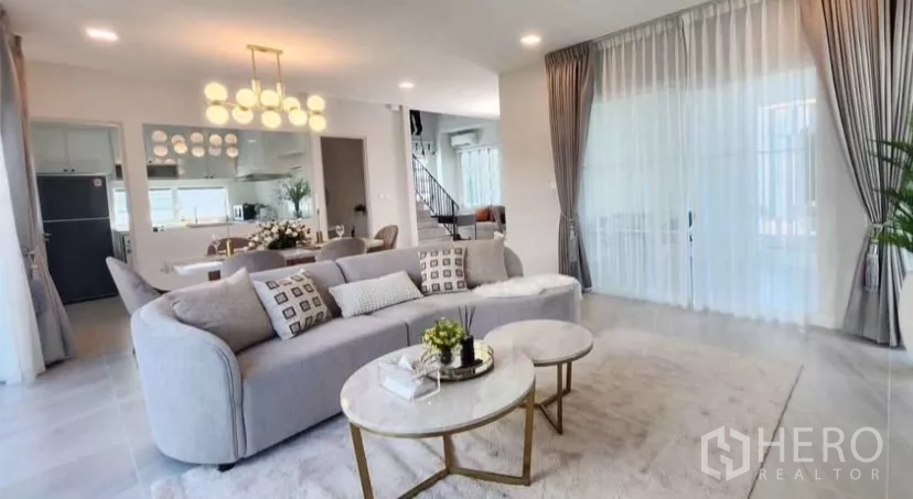 Detached House for rent in Bang Phli, Samut Prakan - Spacious lounge with large windows, staircase and light gray curtains.