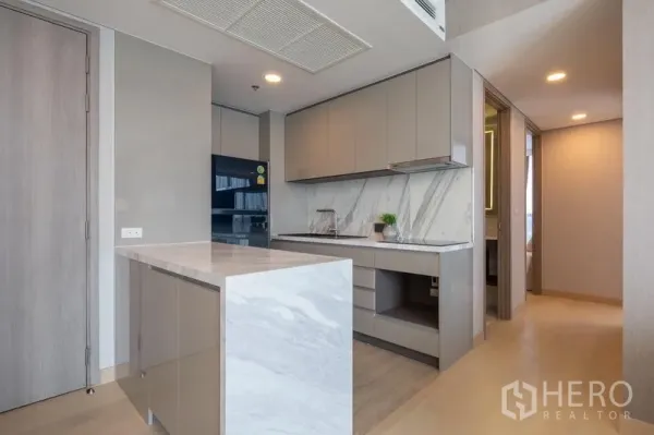 Condominium for rent in Khlong Toei, Bangkok - Contemporary kitchen with marble countertops and backsplash, island bar, built-in cabinetry, and black refrigerator.