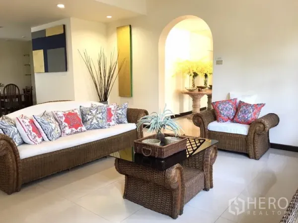 独立式住宅 出租在Phra Khanong, Bangkok - 明亮客厅，藤编沙发组合、彩色抱枕与玻璃茶几。