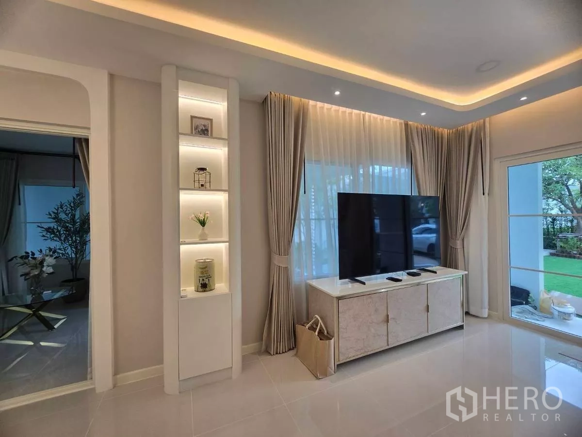 Detached House for rent in Bang Phli, Samut Prakan - Living room featuring TV console, built-in illuminated shelves and full-length curtains.