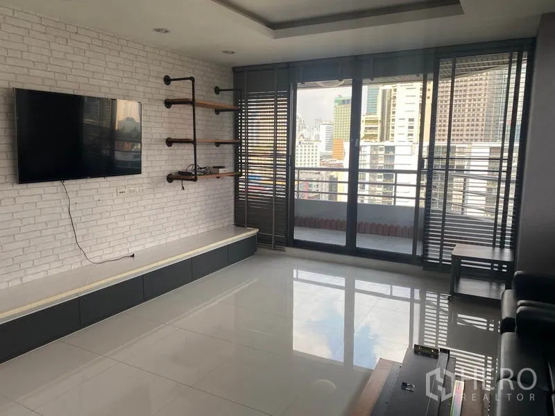 คอนโด ให้เช่าในKhlong Toei, Bangkok - ห้องนั่งเล่นเชื่อมต่อระเบียง ผนังอิฐขาว ทีวีติดผนัง และวิวสกายไลน์