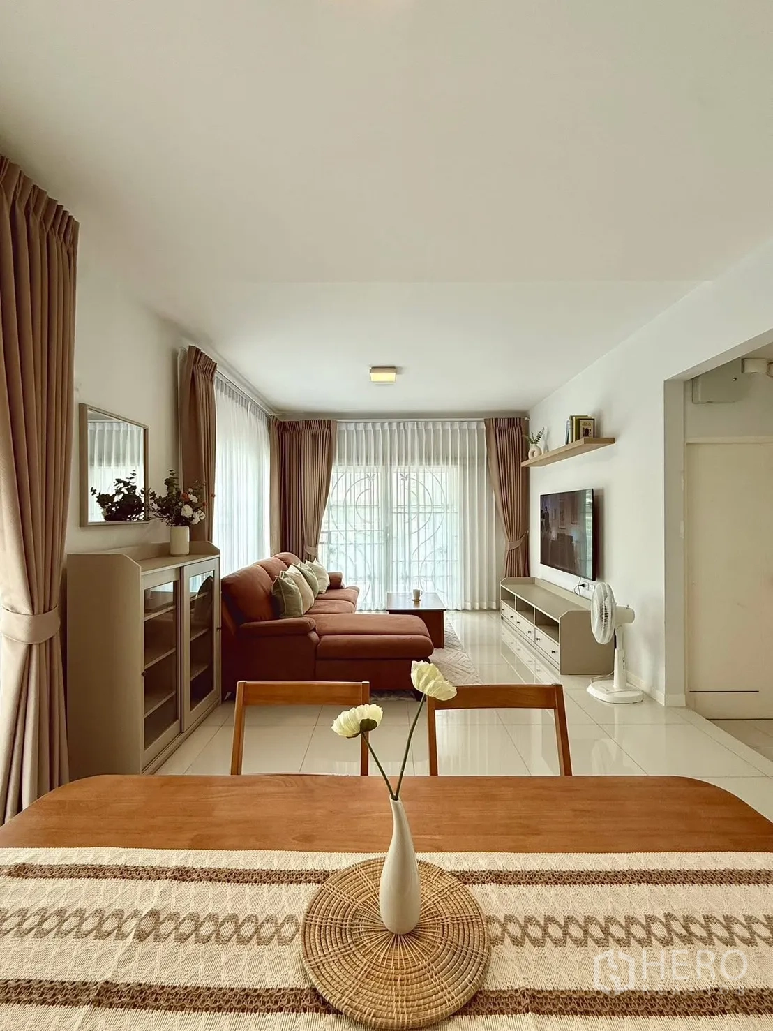 独栋房屋 for rent in Bang Phli, Samut Prakan - 餐桌与花瓶装饰，前方为转角沙发与明亮窗户的起居室。