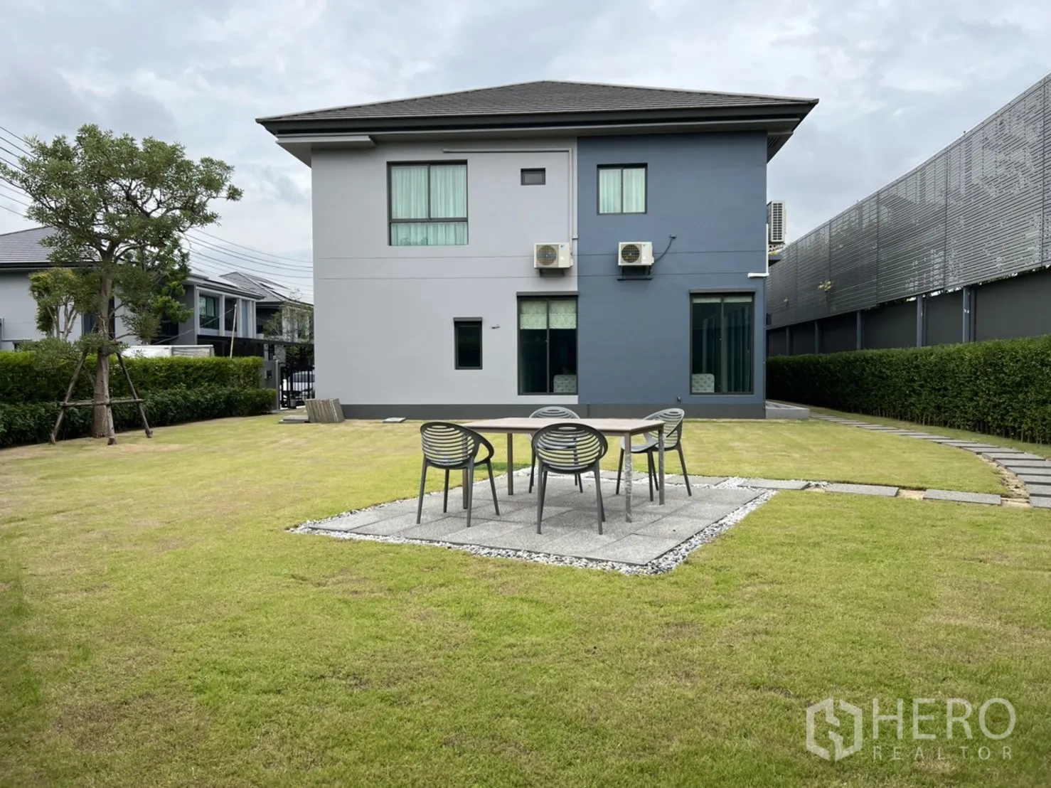 Detached House for rent in Bang Kapi, Bangkok - Expansive back lawn with patio seating, hedges, and the home’s rear façade.
