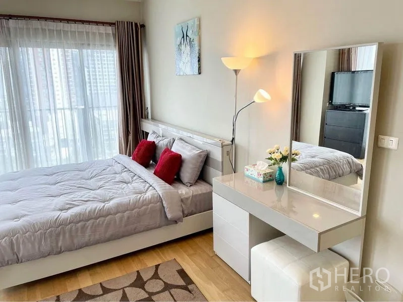 คอนโด ให้เช่าในWatthana, Bangkok - โต๊ะเครื่องแป้งกระจกบานใหญ่ พร้อมสตูล และของตกแต่ง ข้างเตียงหมอนอิงสีแดง