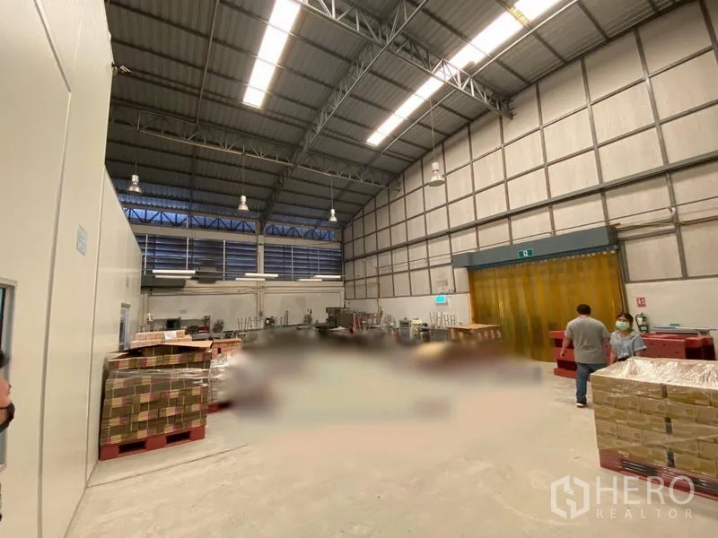 货栈 出租在Bueng Kum, Bangkok - 仓库内部挑高钢结构、百叶窗采光，托盘与黄色PVC帘一角。