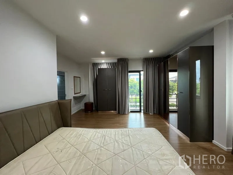 บ้าน ให้เช่าในSaphan Sung, Bangkok - ห้องนอนมาสเตอร์กว้าง พื้นไม้ เตียงใหญ่ ตู้เสื้อผ้า และประตูกระจกออกระเบียงพร้อมผ้าม่าน