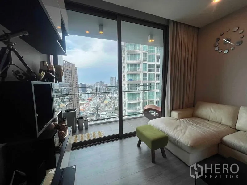 คอนโด ให้เช่าในKhlong Toei, Bangkok - ห้องนั่งเล่นพร้อมโซฟาตัวแอล เชื่อมสู่ระเบียง ชมวิวสกายไลน์กรุงเทพฯ