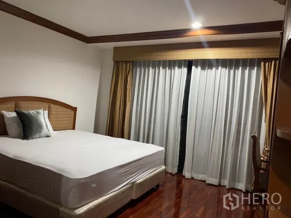 Condominium for rent in Watthana, Bangkok - Bright secondary bedroom with queen bed, wide windows and layered drapes.