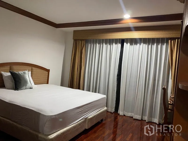 Condominium for rent in Watthana, Bangkok - Bright secondary bedroom with queen bed, wide windows and layered drapes.