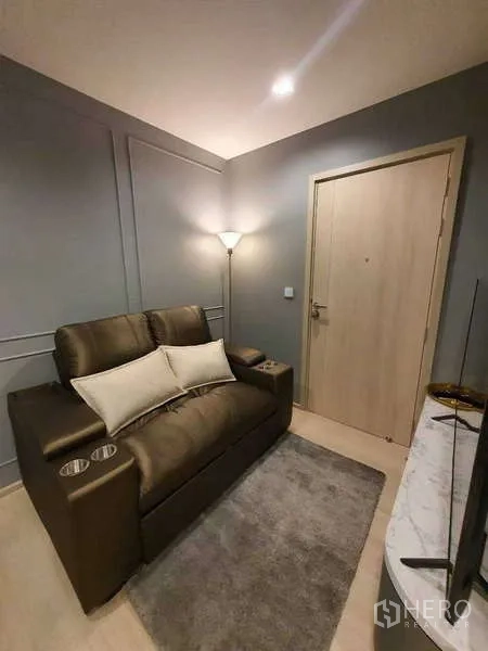 Condominium for rent - Living area with leather loveseat, rug, and minimalist TV unit by the entrance.